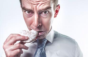 A man looking upset as he eats a cookie