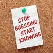 A piece of paper tacked to a cork board, that reads "stop guessing start knowing"